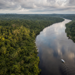 Barco navegando por um rio amazônico próximo à região de fronteira entre Brasil, Colômbia e Peru
