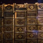 Livros antigos com as obras de Santo Agostinho, dispostos em close sobre uma superfície.
