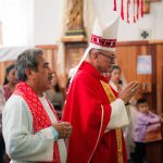 Sacerdote católico usando vestes litúrgicas durante uma cerimônia religiosa em uma igreja.