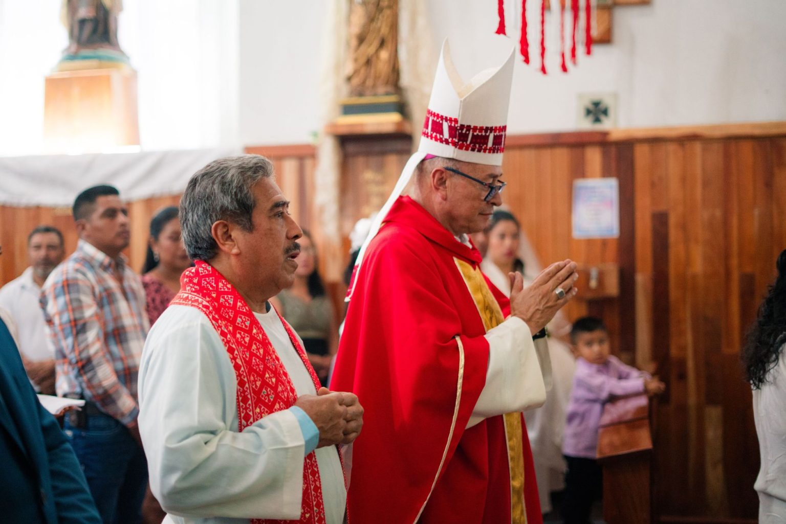Sacerdote católico usando vestes litúrgicas durante uma cerimônia religiosa em uma igreja.