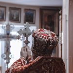 Bispo segurando uma cruz durante uma cerimônia religiosa dentro de uma igreja