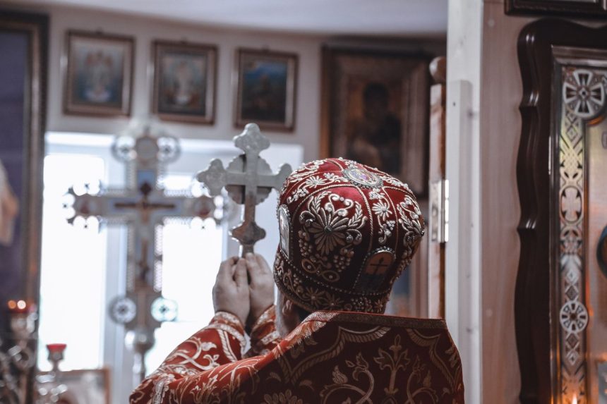 Bispo segurando uma cruz durante uma cerimônia religiosa dentro de uma igreja