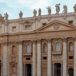 Fachada da Basílica de São Pedro, no Vaticano, com estátuas e colunas sob céu claro