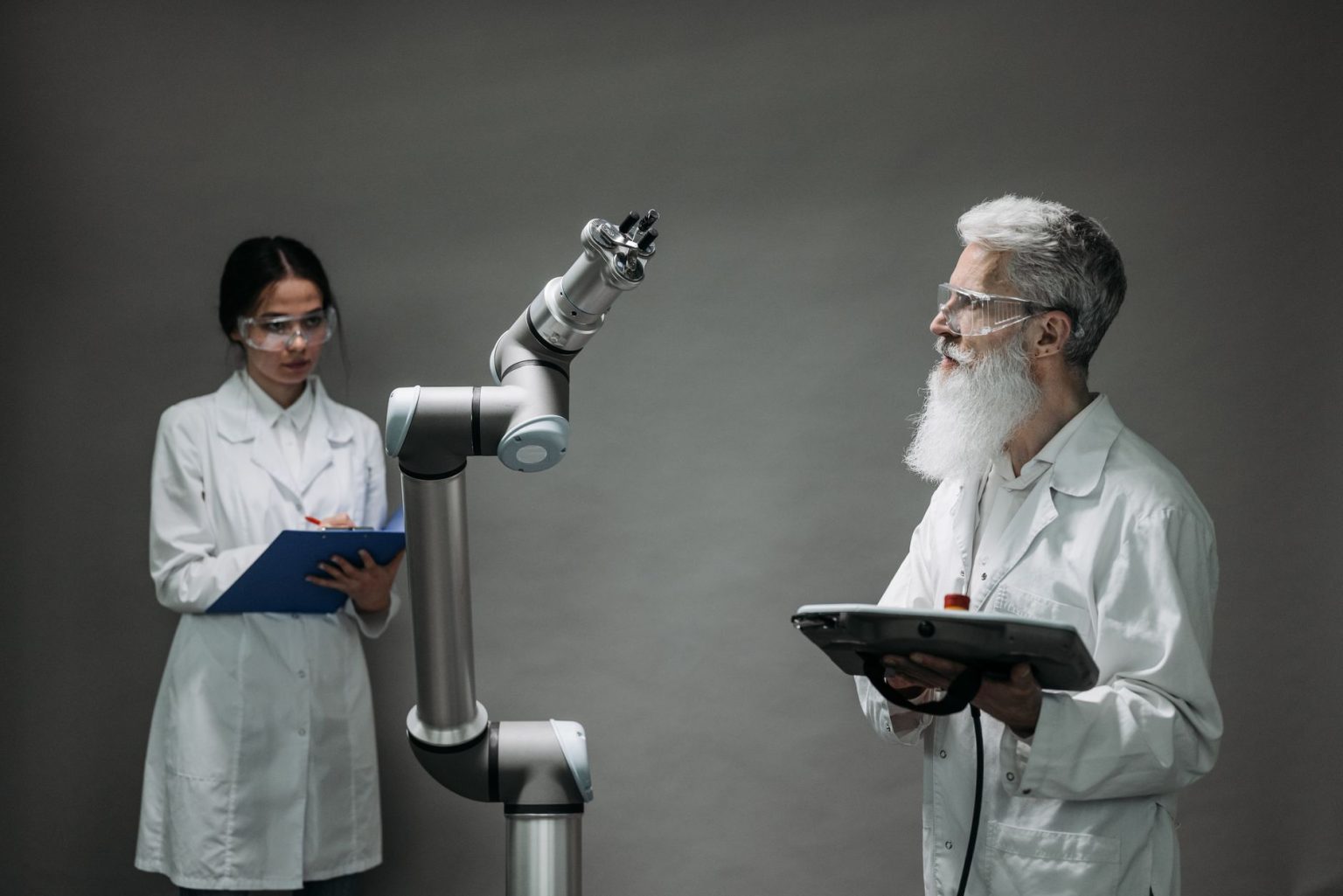 Dois pesquisadores em laboratório analisam um braço robótico durante um trabalho de desenvolvimento tecnológico.