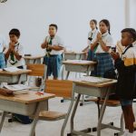 Estudantes uniformizados participam de uma atividade em sala de aula.