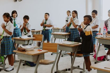 Estudantes uniformizados participam de uma atividade em sala de aula.