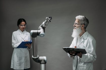 Dois pesquisadores em laboratório analisam um braço robótico durante um trabalho de desenvolvimento tecnológico.